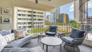 A balcony with a ceiling fan, wicker furniture, and a view of high-rise buildings. - Waikiki Penthouse, 1 Free Parking, 3bdrm, Sleeps 6 (Honolulu)