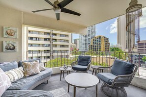 A balcony with a ceiling fan, wicker furniture, and a view of high-rise buildings. - Waikiki Penthouse, 1 Free Parking, 3bdrm, Sleeps 6 (Honolulu)