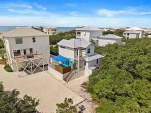 A coastal residential area with multiple two-story houses featuring balconies, a covered outdoor seating area, and a view of the ocean. - A Salty Mate (Beach House Escape Guest House) (Gulf Shores)