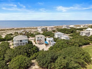 Un quartier résidentiel situé sur la côte, avec de nombreuses maisons, dont certaines dotées de balcons, et une plage en arrière-plan.
