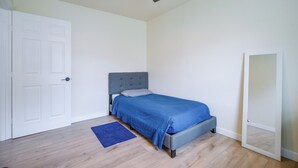 Un dormitorio con cama, ventilador de techo, puerta y espejo.