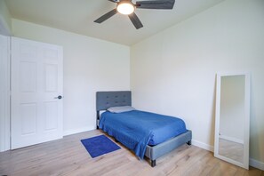 A bedroom with a bed, a ceiling fan, a door, and a mirror. - Near San Antonio River Walk w/ Fenced Yard (San Antonio)