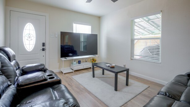 Una sala de estar con televisor, sofás de cuero, una mesa de centro y un ventilador de techo.