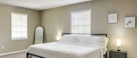 A bedroom with a bed, bedside tables, a window, and a wall-mounted light fixture.