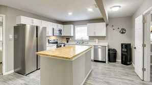 Una cocina moderna con una isla central, electrodomésticos de acero inoxidable y vistas al área de estar.