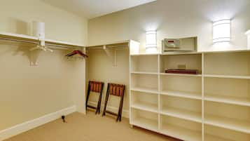 A room with a built-in shelving unit, a coat rack, and two chairs.