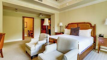 A hotel room with a large bed, two armchairs, a nightstand, and a desk.