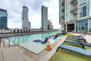 Ein Pool auf dem Dach mit Liegestühlen und Blick auf die umliegenden Hochhäuser.