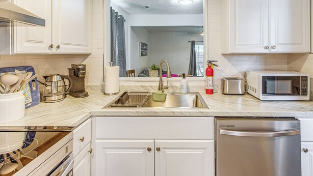 A modern kitchen with white cabinetry, a stainless steel sink, a microwave, and a toaster. - Steps to Sea & Sand! Family Haven in Myrtle Beach (Myrtle Beach)