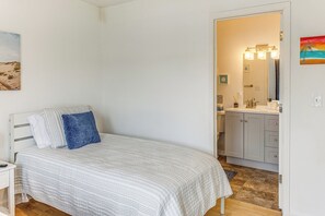 Ein Schlafzimmer mit Bett, Nachttisch, Waschtisch und Bad mit Waschbecken und Spiegel.