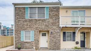 A two-story building with a brick facade, a front door, and a small balcony. - Steps to Sea & Sand! Family Haven in Myrtle Beach (Myrtle Beach)