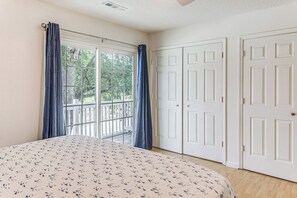 A bedroom with a large bed, a sliding glass door leading to a balcony, and two white doors. - Steps to Sea & Sand! Family Haven in Myrtle Beach (Myrtle Beach)
