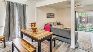 A dining area with a wooden table and benches, a grey sofa, and a painting on the wall. - Steps to Sea & Sand! Family Haven in Myrtle Beach (Myrtle Beach)