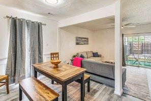 Ein Essbereich mit einem Holztisch, Bänken, einem grauen Sofa und einem Bild an der Wand.