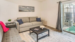A living room with a sofa, a coffee table, and a painting on the wall. - Steps to Sea & Sand! Family Haven in Myrtle Beach (Myrtle Beach)