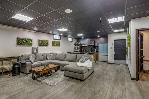 Una sala de estar moderna con un sofá seccional, una mesa de centro y una cocina al fondo.