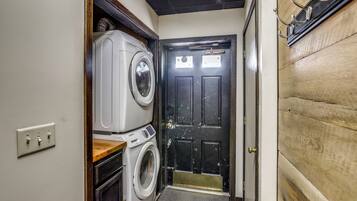 A compact laundry room with a washing machine, dryer, and a door with a brass handle.