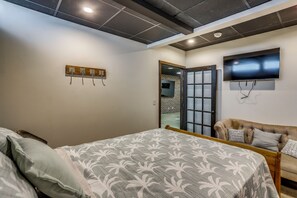 Un dormitorio con cama, sofá, televisor e iluminación empotrada en el techo.