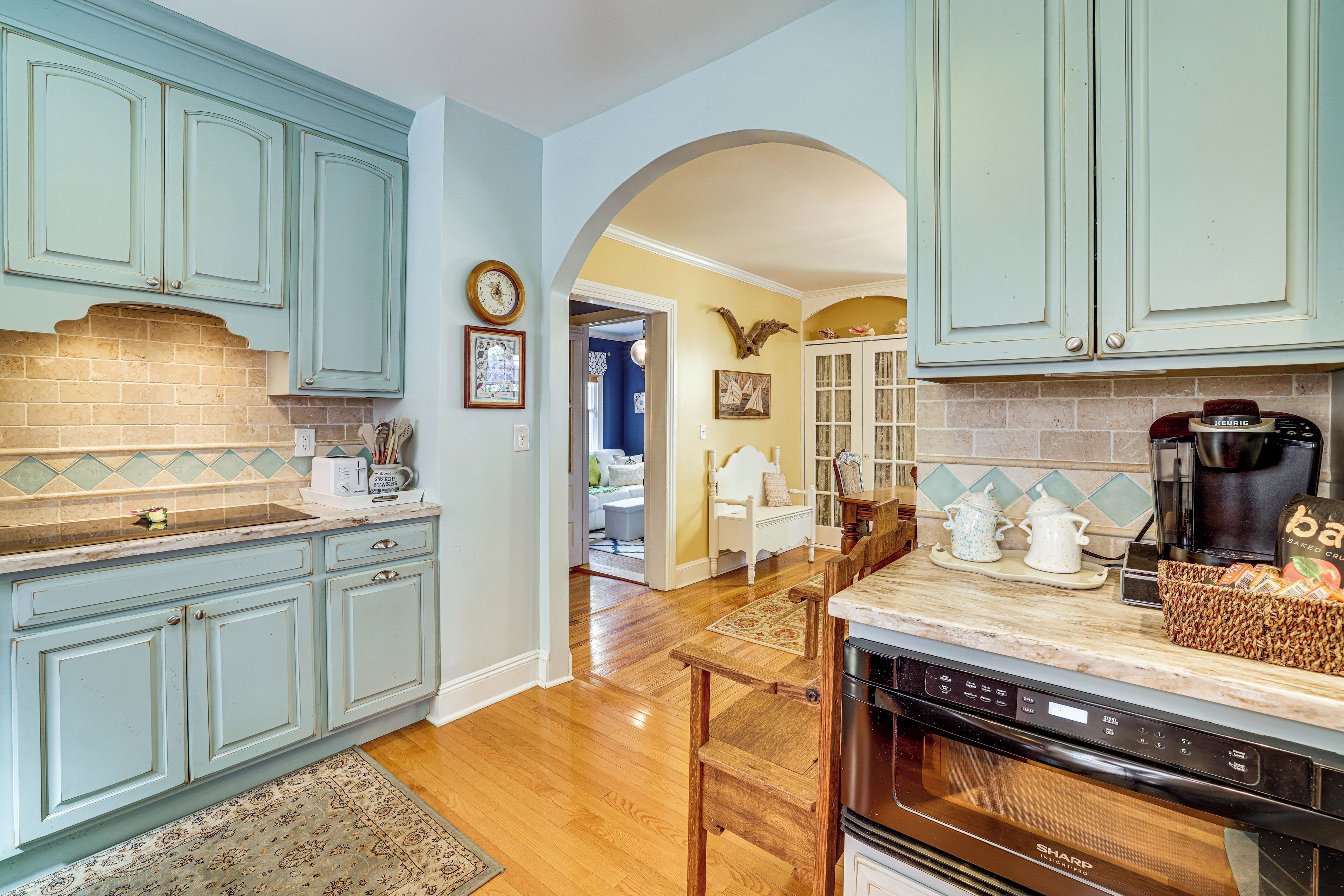 A kitchen with light blue cabinets, a coffee maker, and a microwave.