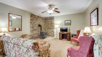 A living room with a stone wall, a fireplace, a television, and floral-patterned furniture.