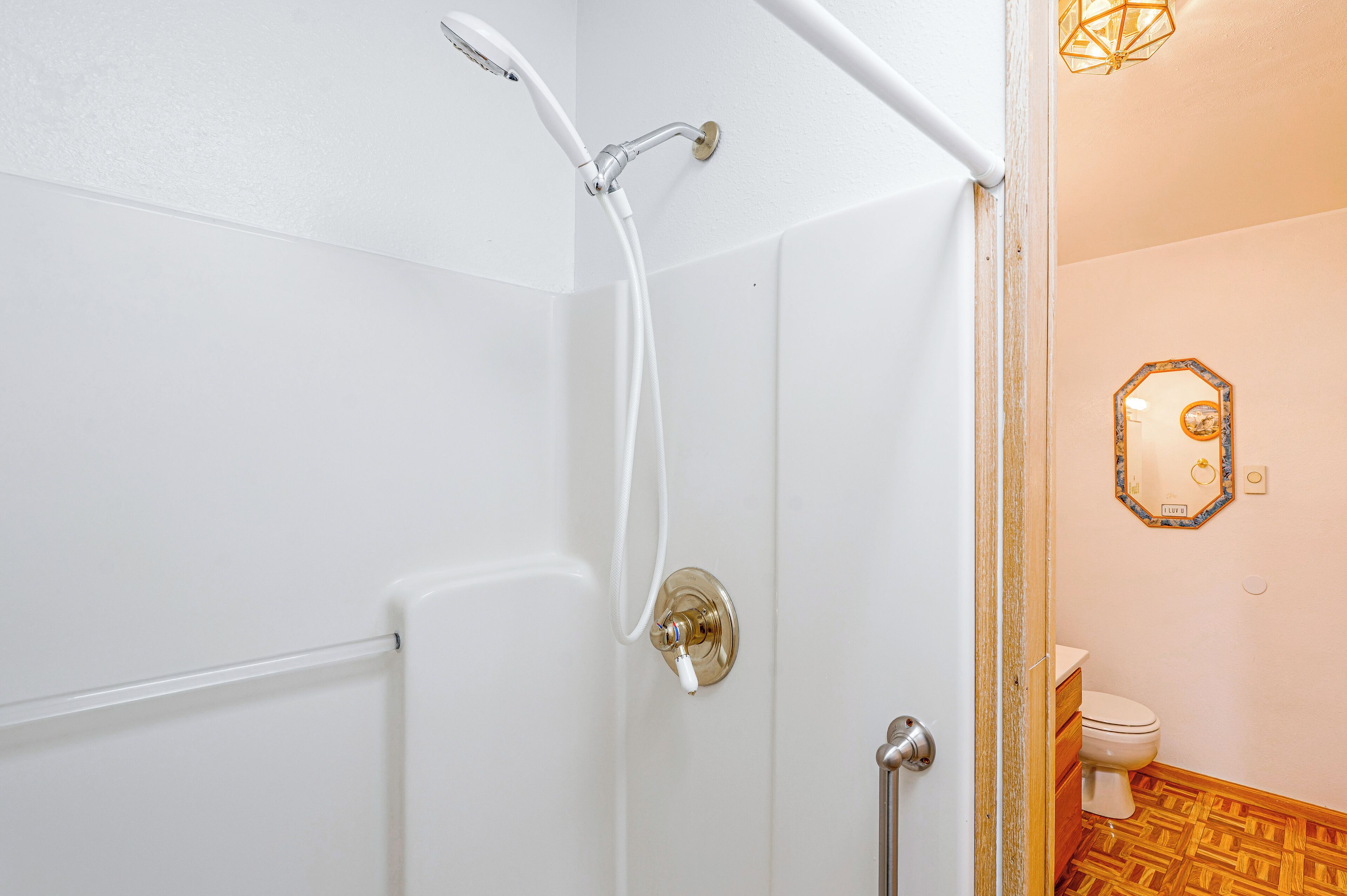 Een badkamer met een douche, toilet en een spiegel met decoratieve lijst.