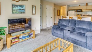 Ein Wohnzimmer mit Fernseher, einer Couch und einem Bücherregal.