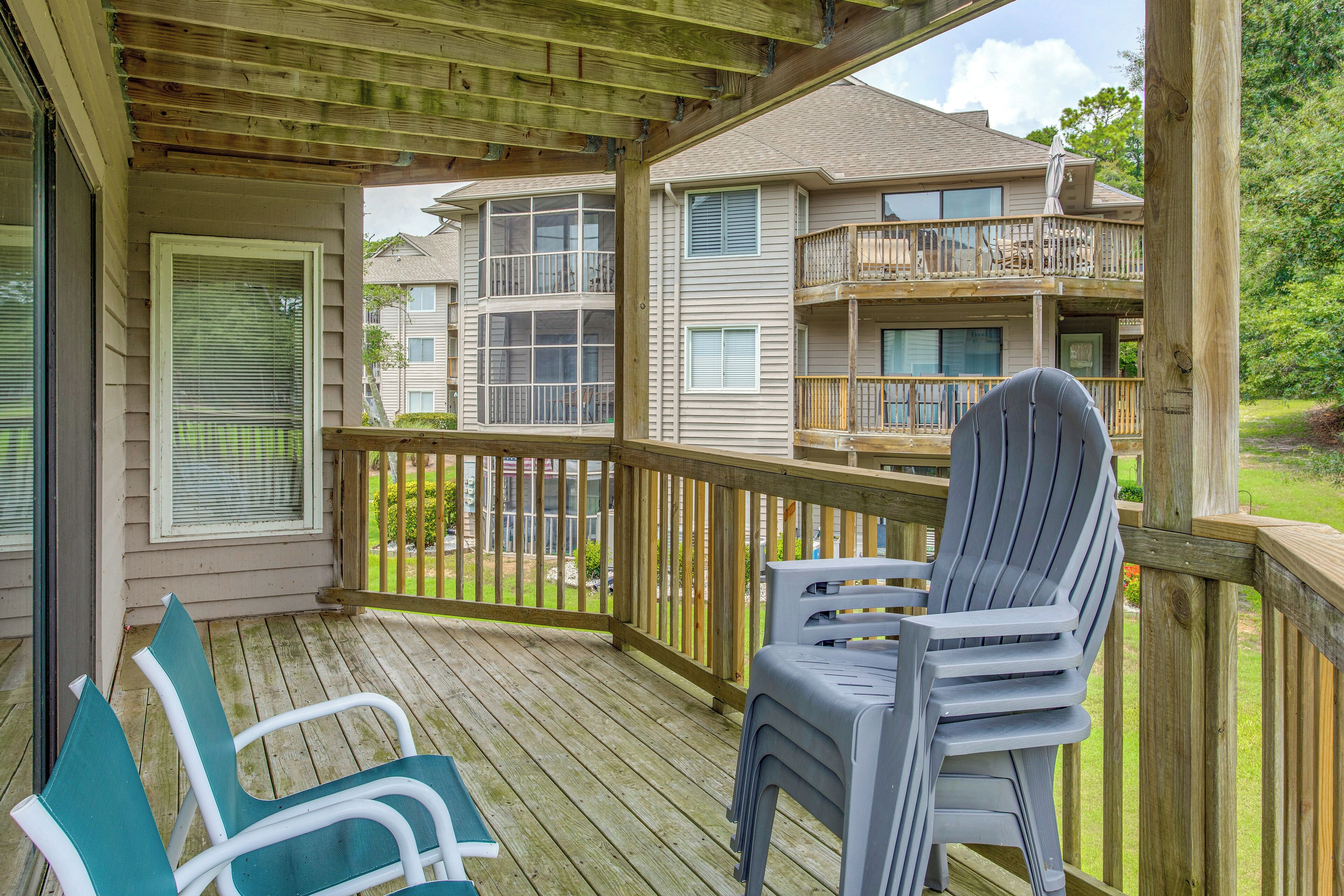A wooden deck with a covered area, a chair, and a table.