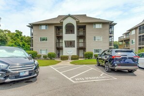 A multi-story building with a parking lot marked 'NO PARKING' and a Ford SUV parked in the lot. - Near Golf! Waterfront Unit w/ Pool in Sunset Beach (Sunset Beach)