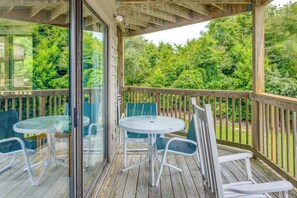A covered outdoor area with a wooden deck, glass doors, and a table with chairs. - Near Golf! Waterfront Unit w/ Pool in Sunset Beach (Sunset Beach)