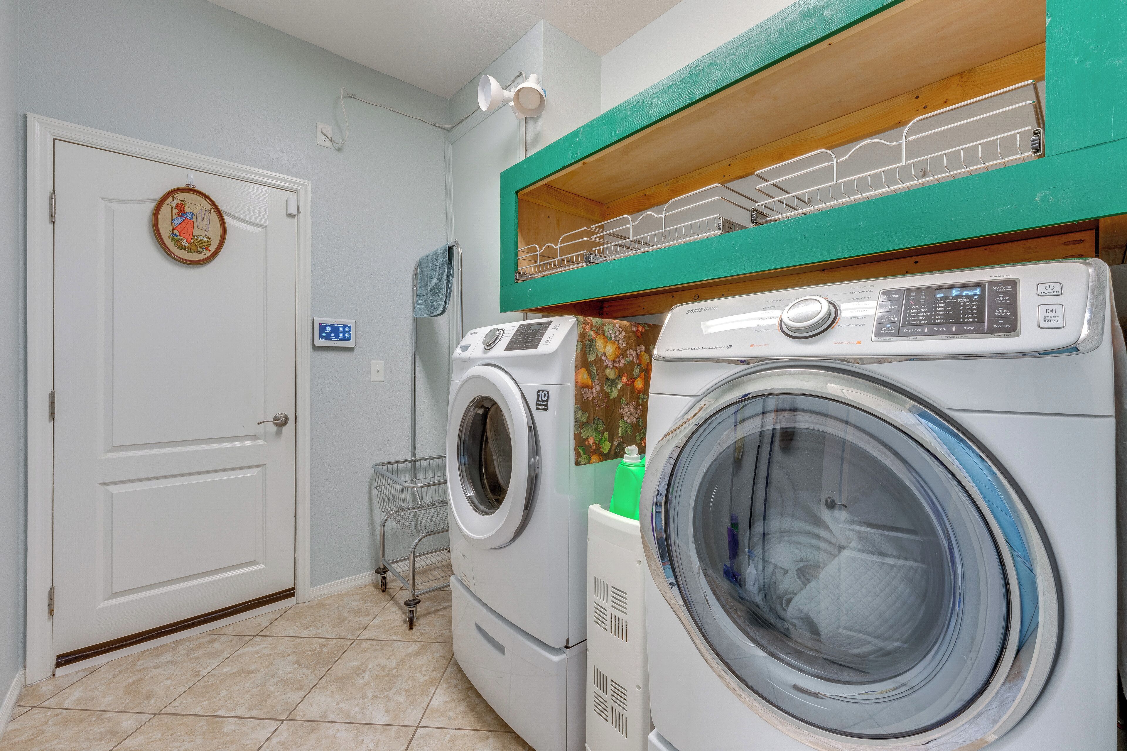 Een wasserij met twee voorladers, een droogrek en een deur met een decoratief bord.
