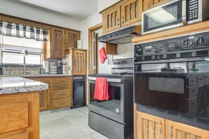 Une cuisine avec des meubles de rangement en bois, un four à micro-ondes, une cuisinière et un lave-vaisselle.