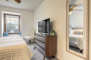 Une chambre à coucher avec un grand lit, une commode, une télévision et un miroir.