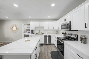 A modern kitchen with white cabinetry, a central island, stainless steel appliances, and a marble countertop. - Pool & Hot Tub Access! Superstition Mtn Condo (Apache Junction)