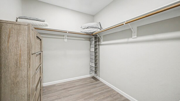 Huoneen nurkka, jossa on puinen vaatekaappi, valkoinen seinä ja puulattia.