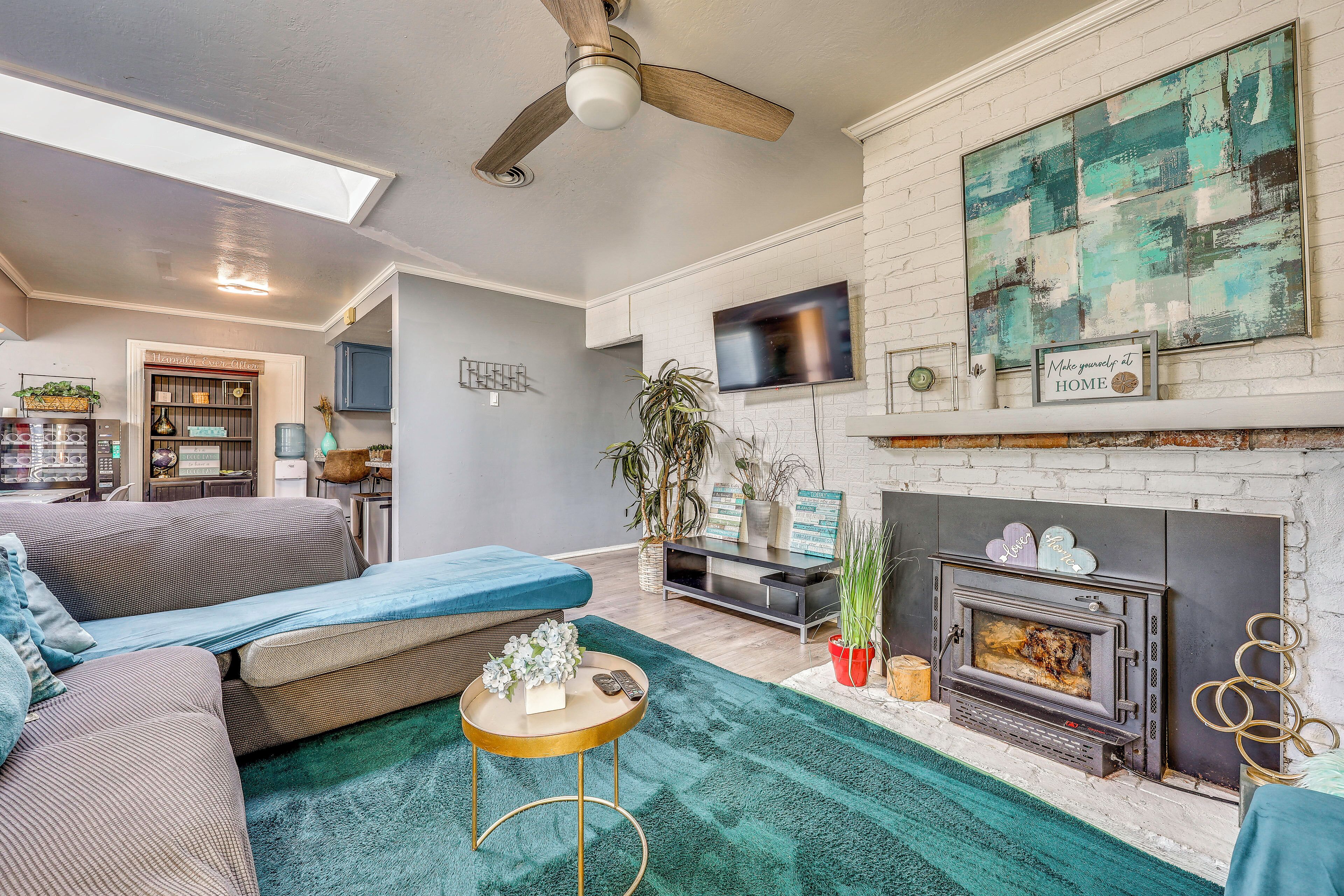 A living room with a sofa, a coffee table, a fireplace, and a television mounted on the wall.