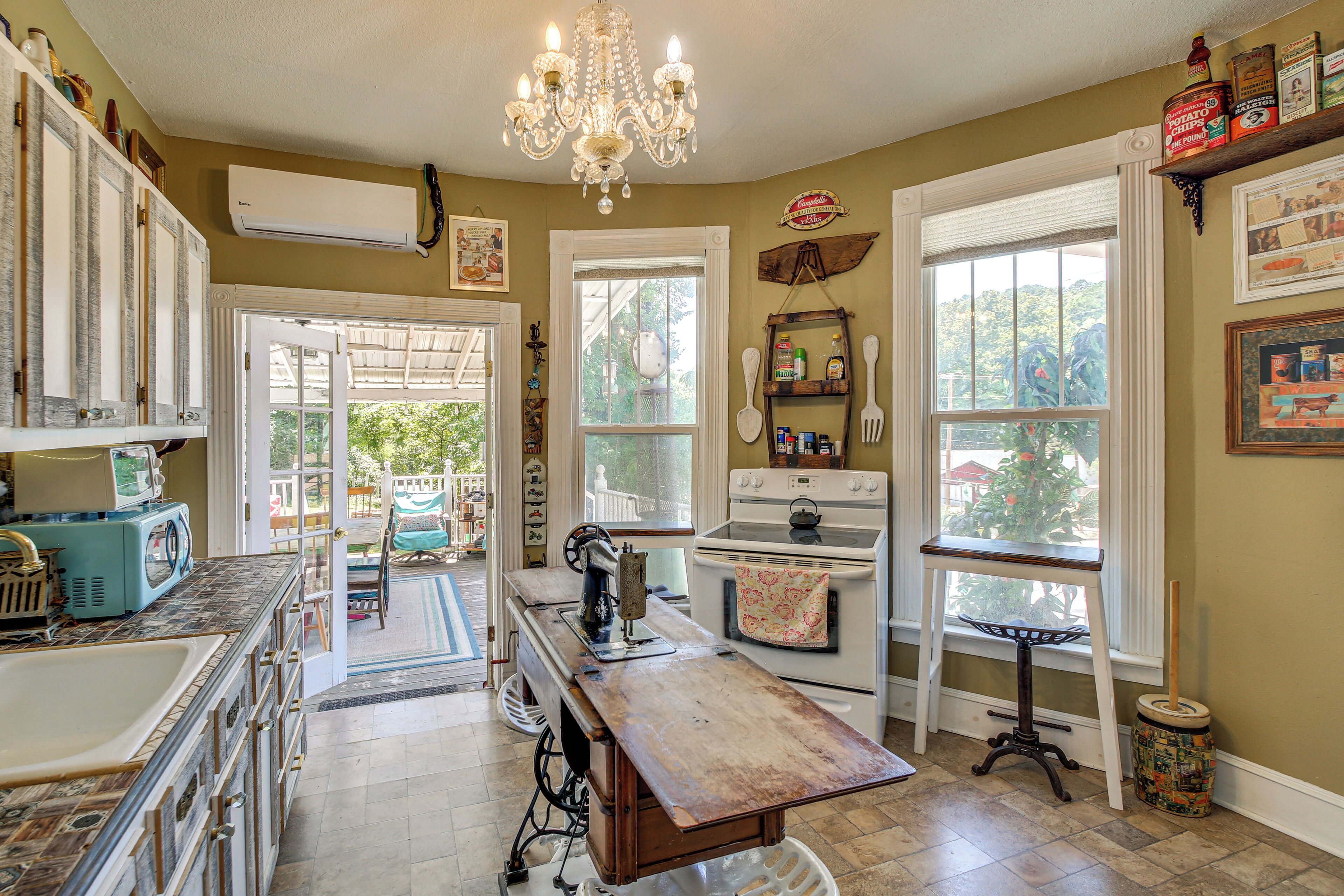 A kitchen with a vintage stove, a chandelier, and a view of the outdoors.