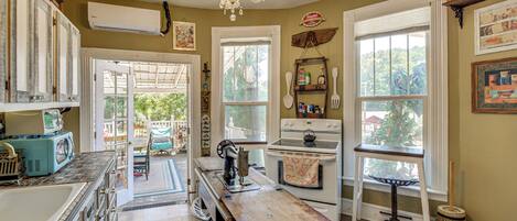 A kitchen with a vintage stove, a chandelier, and a view of the outdoors.