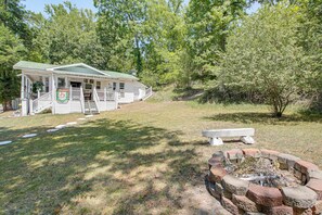 A rustic cabin with a porch, a fire pit, and a grassy yard. - Walk to Bathhouse Row! Historic Gem w/ Yard (Hot Springs)