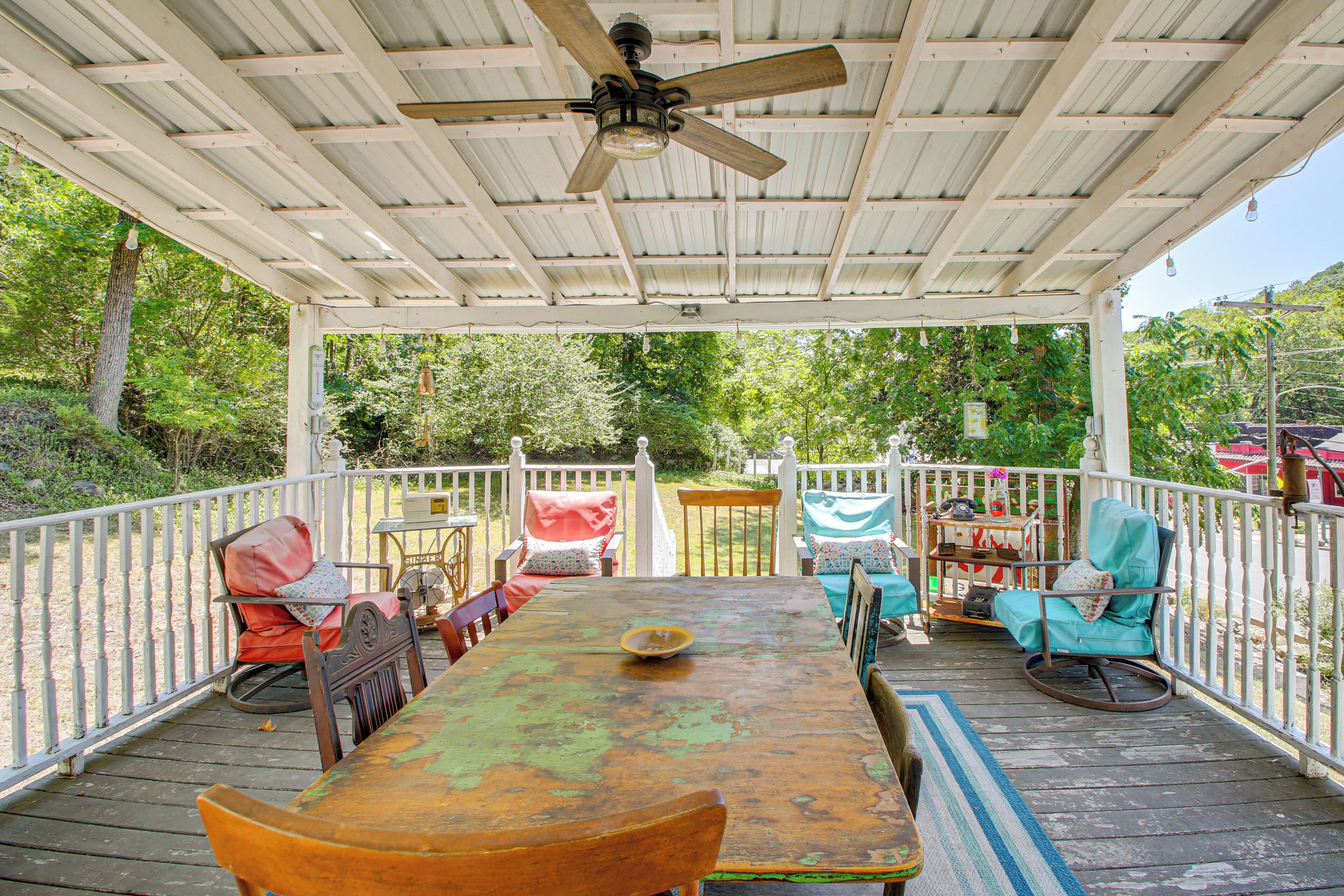 A covered outdoor patio with a table and chairs, surrounded by a white fence.