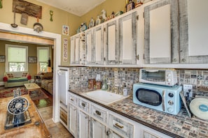 A kitchen with a vintage aesthetic, featuring a white sink, a blue microwave, and a toaster. - Walk to Bathhouse Row! Historic Gem w/ Yard (Hot Springs)