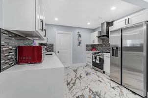 A modern kitchen with a stainless steel refrigerator, a red appliance, and a black oven.