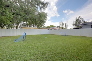 A backyard with a fenced area, a soccer goal, and a tree.