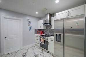 Eine moderne Küche mit weißen Schränken, einem Edelstahl-Kühlschrank, einer roten Mikrowelle und einer gefliesten Spritzschutzwand.
