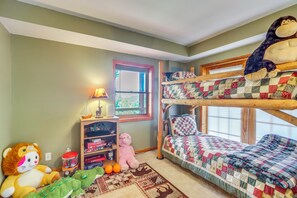 Ein Kinderzimmer mit Etagenbetten, einem Fenster, einem Bücherregal und einem Stofftier.