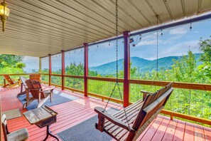 A covered outdoor deck with wooden furniture, a swing, and a view of a mountainous landscape. - Stunning Views & Sunrises! Pappy's Place in Murphy (Murphy)