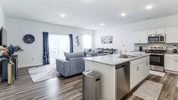 A modern kitchen with white cabinets, a stainless steel dishwasher, and a built-in oven.