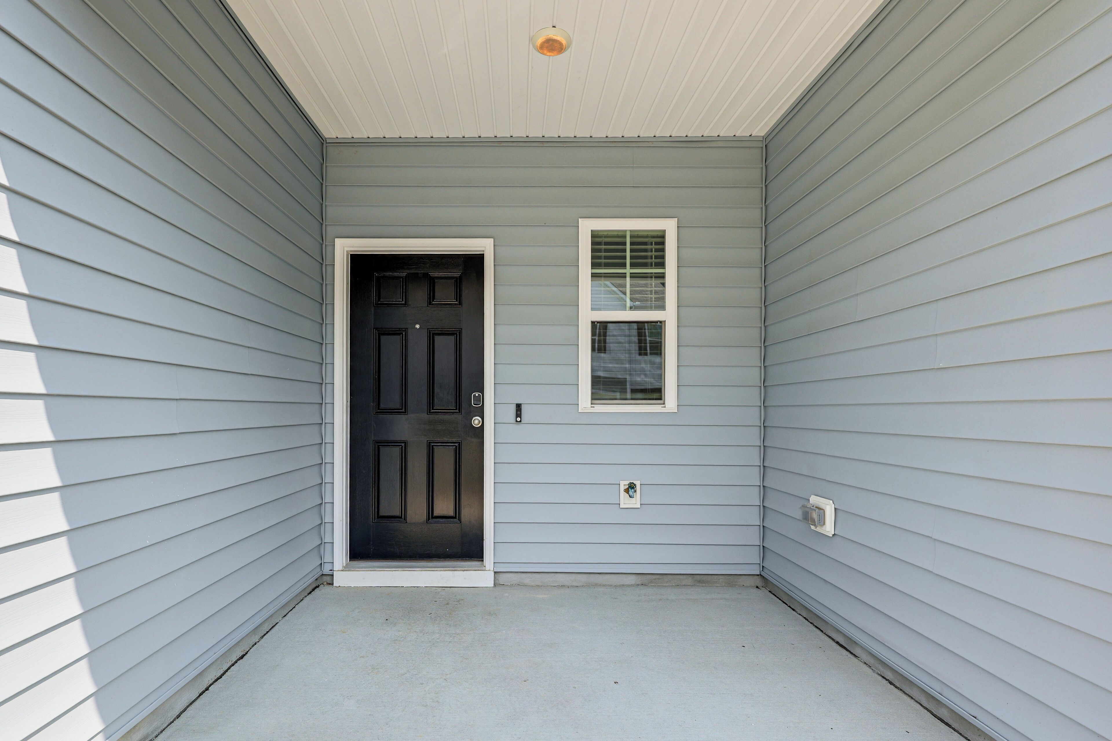 A grey exterior wall with a black door and a small window.