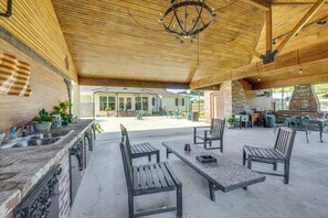 An outdoor patio with a brick wall, a wooden ceiling, and a grill area.