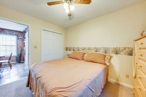 A bedroom with a bed, dresser, and a ceiling fan.