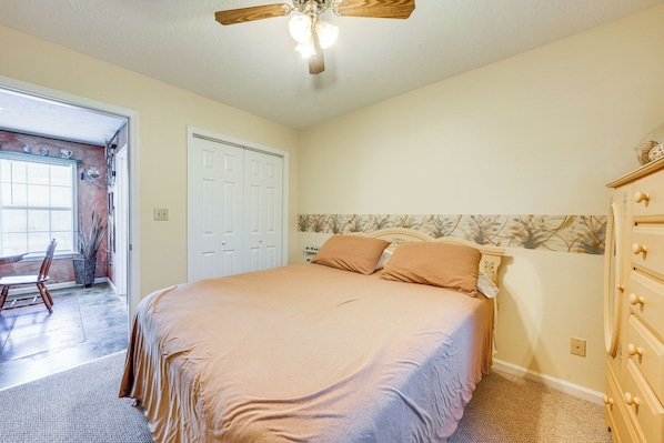 A bedroom with a bed, dresser, and a ceiling fan.